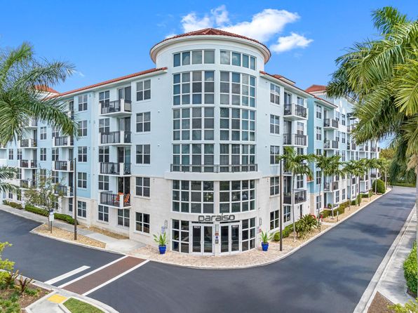 Modern apartment building exterior with glass windows and palm trees managed by Threshold Management