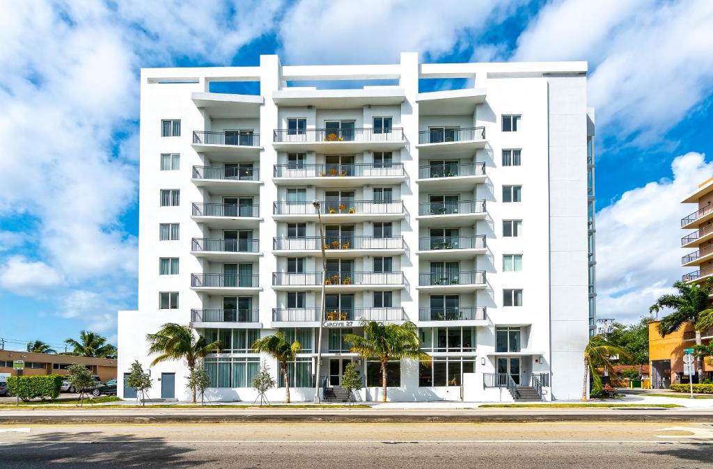 Front facade of a white eight‑story Downtown Miami condominium with balconies against a partly cloudy sky.
