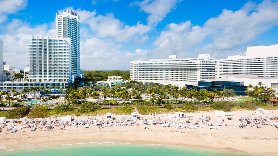 Aerial view of Fontainebleau Miami Beach hotel managed by Threshold Management with beach, palm trees, and sun loungers