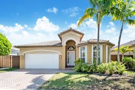 Exterior view of a Doral single‑family home with red‑tile roof, manicured lawn, and palm trees.
