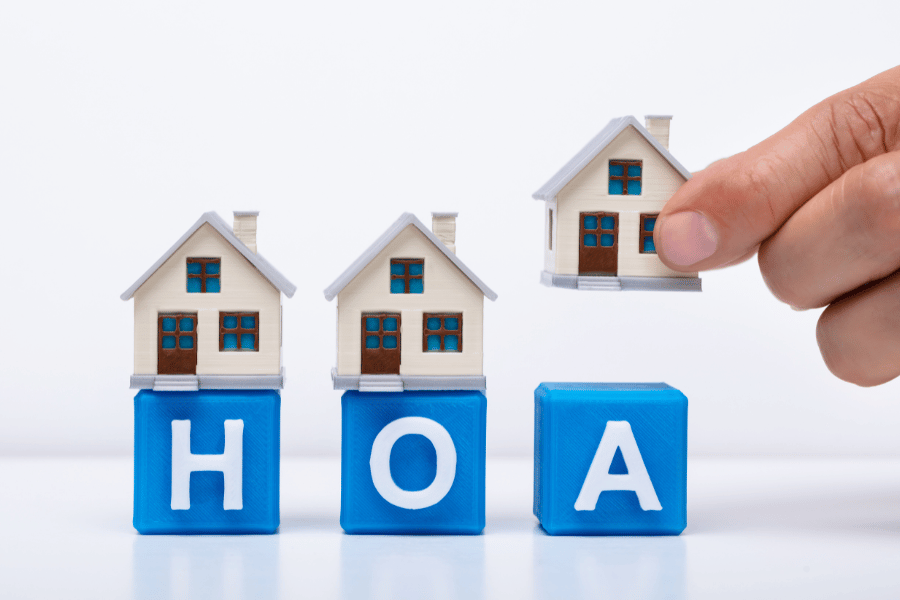 Miniature houses on blue blocks spelling HOA – Homeowners Association concept by Threshold Property Management