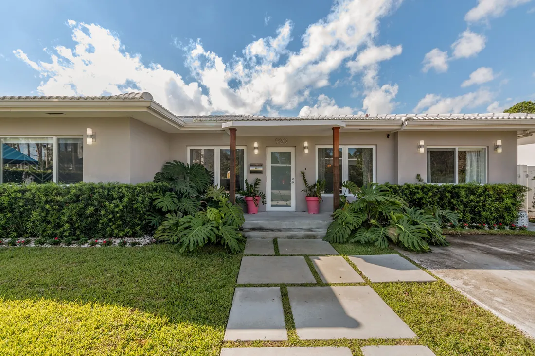 Single-story home with landscaped front yard and tropical plants in a quiet Miami Beach neighborhood.