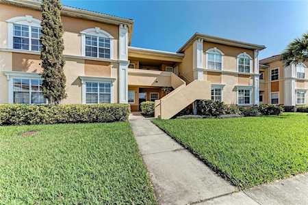 Front view of a two-story multifamily apartment complex with stucco finish, central staircase, and manicured lawn in Palmetto Bay, Florida