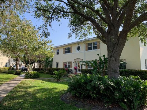 Two-story garden-style apartment building with lush landscaping and mature shade trees in Miami Shores, Florida