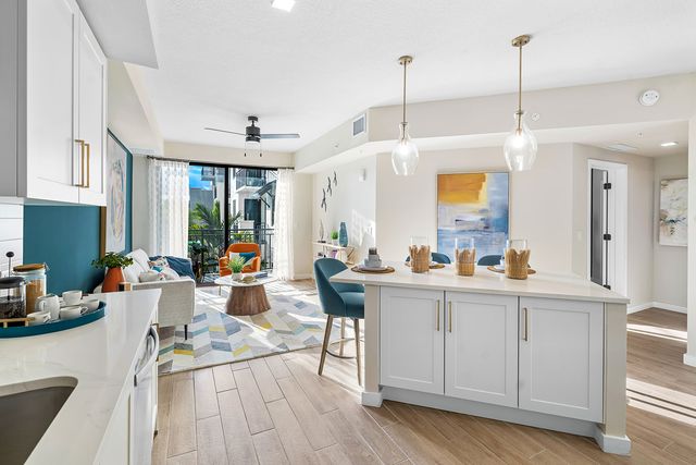 Bright open-concept kitchen and dining area with white cabinets, pendant lighting, and modern decor in a Palmetto Bay home
