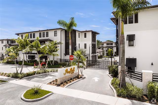 Modern gated apartment complex with palm trees and landscaped entrance in Kendall, Florida